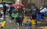 Pedestrians walk along a flooded sidewalk, September 29, 2023, in the Brooklyn borough of New York. (AP Photo/Jake Offenhartz)