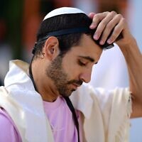 Illustrative: A Jewish man prays with tefillin and prayer shawl at a mass prayer for in Habima Square in Tel Aviv on August 2, 2023. (Tomer Neuberg/Flash90)