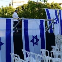 Activists from the Rosh Yehudi organization set up a 'mechitzah' divider made of Israeli flags ahead of a public prayer event in Dizengoff Square, Tel Aviv, on Yom Kippur eve. September 24, 2023. (Tomer Neuberg/Flash 90)