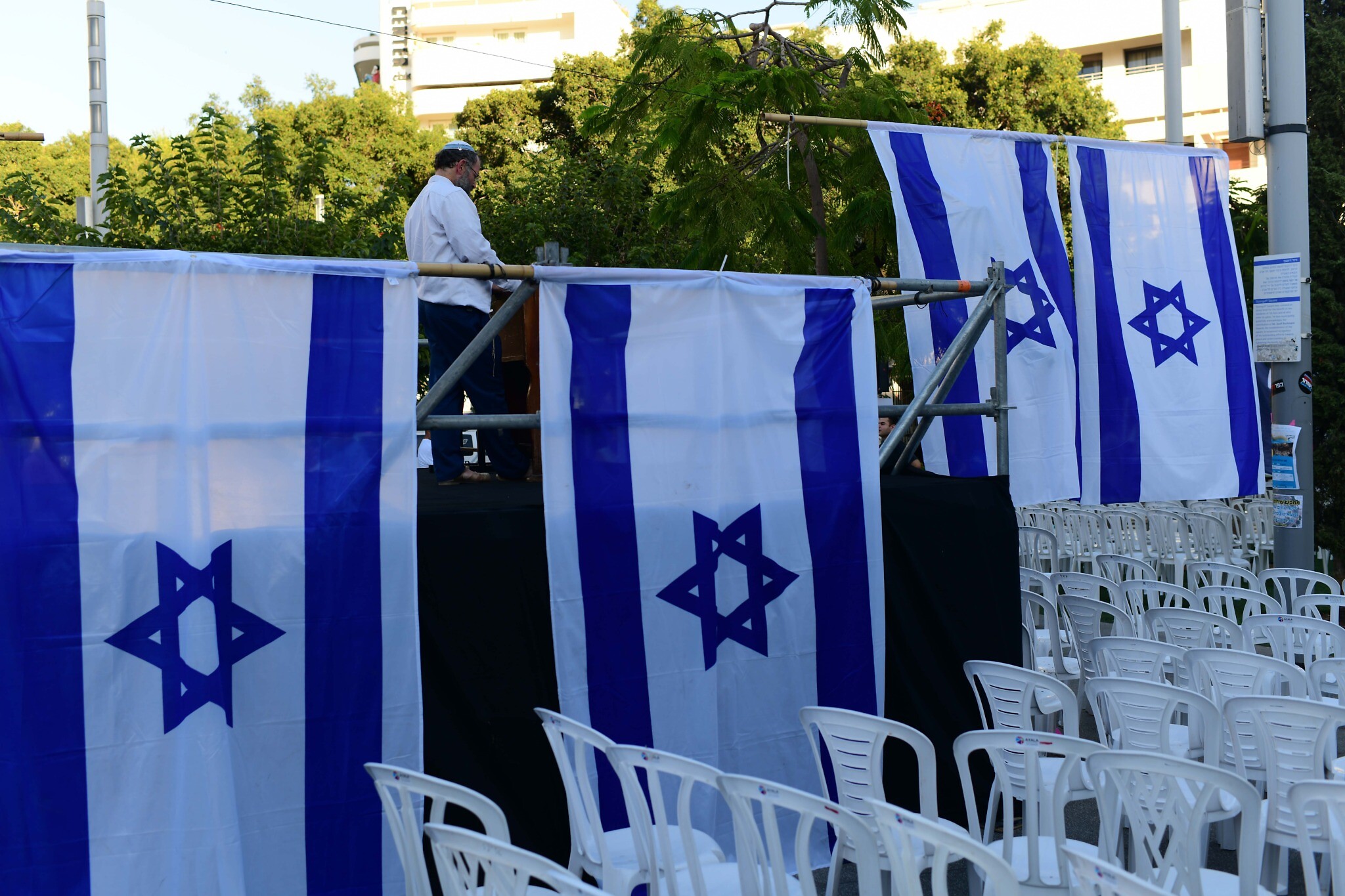 Activists from the Rosh Yehudi organization set up a 'mechitzah' divider made of Israeli flags ahead of a public prayer event in Dizengoff Square, Tel Aviv, on Yom Kippur eve. September 24, 2023. (Tomer Neuberg/Flash 90)