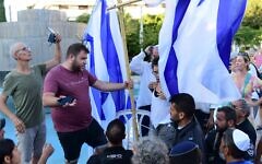 Secular activists take down a gender divider made of Israeli flags that was set up by the Rosh Yehudi group in defiance of a High Court order at a public prayer service in Dizengoff Square, Tel Aviv on Yom Kippur. September 24, 2023. (Tomer Neuberg/Flash90)