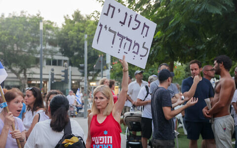 People pray while activists protest against gender segregation in the public space during a public prayer on Dizengoff Square in Tel Aviv, on Yom Kippur, the Day of Atonement, September 25, 2023. The sign reads 'Strictly secular.' ( Itai Ron/Flash90)