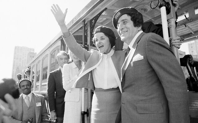 San Francisco Mayor Dianne Feinstein and singer Tony Bennett, who sang "I Left My Heart in San Francisco," hang onto the outside of a cable car in San Francisco before taking a test ride, May 2, 1984. (AP Photo/Jeff Reinking, File)