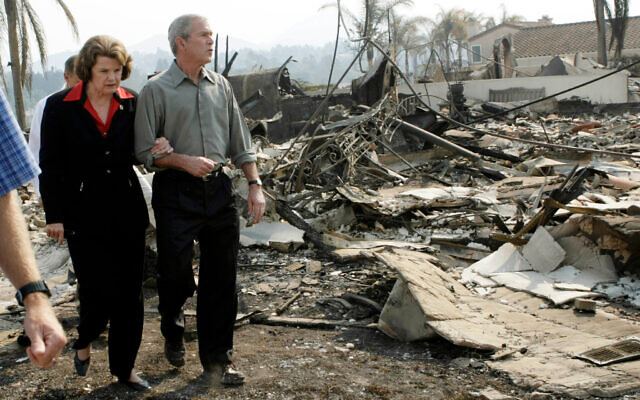 President George W. Bush, right, escorts US Sen. Dianne Feinstein as they walk through the remains of a home that was damaged by the California wildfires, October 25, 2007, in San Diego. (AP Photo/Pablo Martinez Monsivais, File)