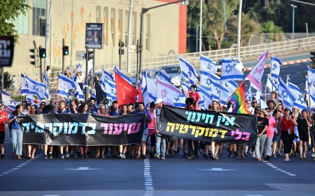 Protesters against the coalition's judicial overhaul legislation march in the central city of Rehovot on September 2, 2023, carrying signs reading: "There is no education without democracy" (right) and "A lesson in democracy." (Roby Yahav)
