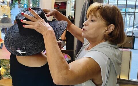 Dalia Varman (right) helps a customer with her selection, at Dalia's Hats in Tel Aviv. (Gavriel Fiske/Times of Israel)