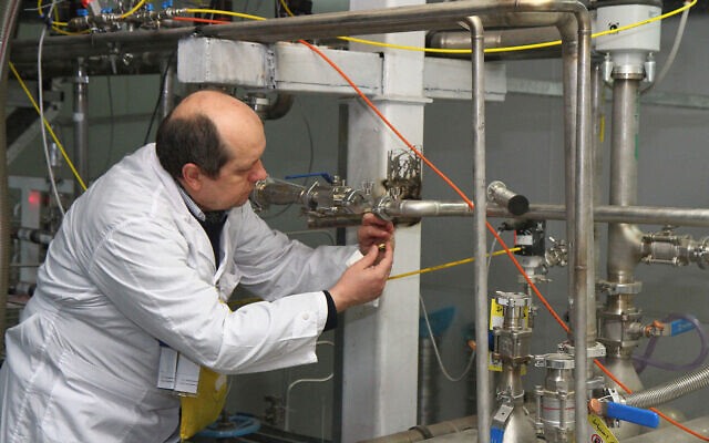 An unidentified International Atomic Energy Agency (IAEA) inspector disconnects the connections between the twin cascades for 20 percent uranium production at the nuclear research centre of Natanz, some 300 kilometers south of Tehran, Iran, on January 20, 2014. (KAZEM GHANE/IRNA/AFP)