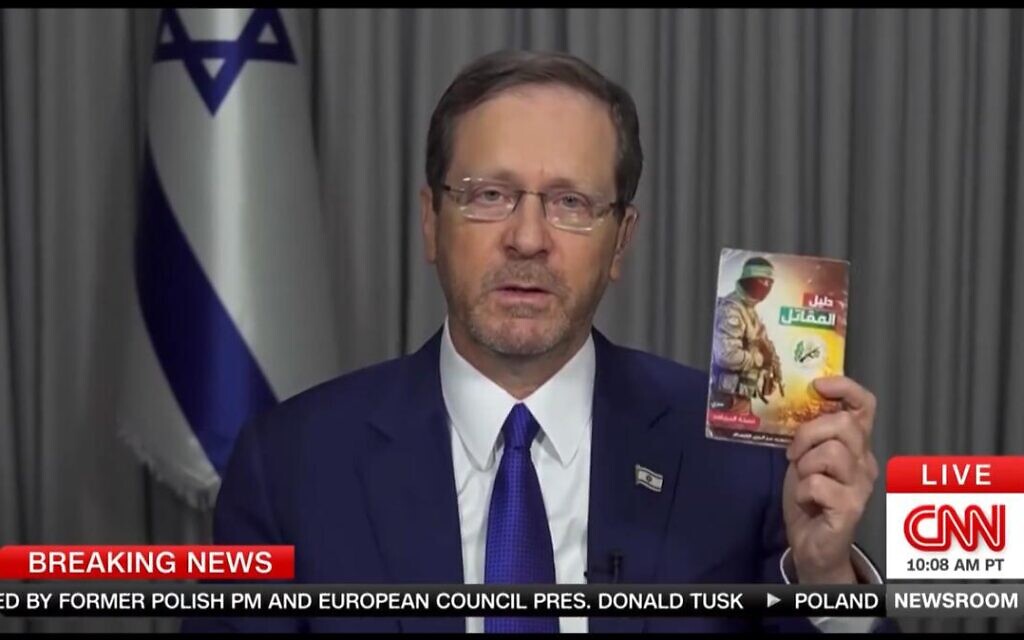 President Isaac Herzog shows a terror manual on how to kidnap and torture people taken from the body of a Hamas terrorist, in an interview with CNN on October 15, 2023 (Screencapture)