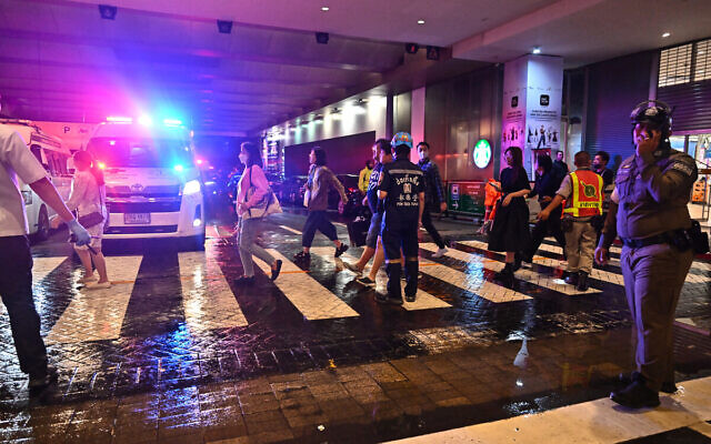 Emergency workers and police direct people leaving Siam Paragon shopping center in Bangkok on October 3, 2023, following a shooting incident in the mall. (Lillian Suwanrumpha/AFP)