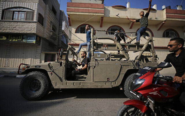 Palestinians return to Gaza City driving an Israeli Humvee that was seized after terrorists entered Israel by land on October 7, 2023. (MAJDI FATHI / AFP)