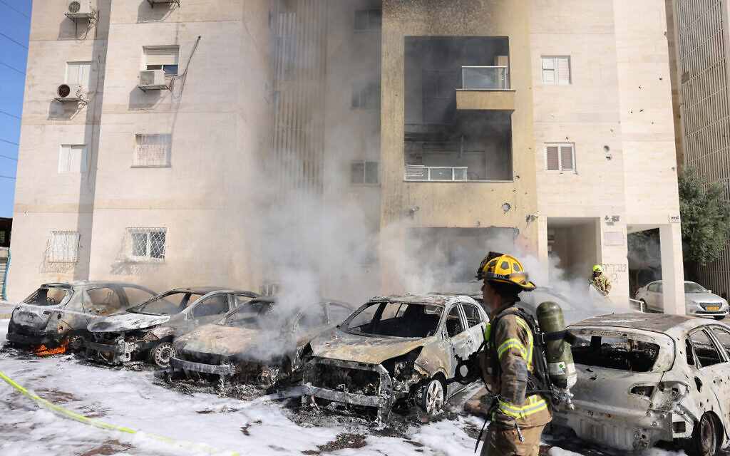 Israeli fire brigade teams douse the blaze in a parking lot outside a residential building following a rocket attack from the Gaza Strip in the southern Israeli city of Ashkelon, on October 7, 2023. (AHMAD GHARABLI / AFP)