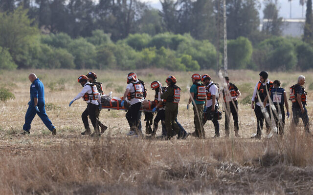 Israeli rescue teams evacuate a wounded person near the southern city of Sderot on October 7, 2023, after the Palestinian terror group Hamas launched a large-scale surprise attack on Israel, firing a barrage of rockets from Gaza and sending ground units to kill or abduct Israelis. (Menahem Kahana/AFP)