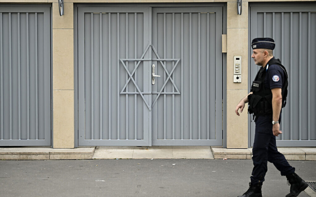 A French policeman stands guard outside a synagogue, two days after security measures have been reinforced near Jewish temples and schools, in central Paris, on October 9, 2023. (Photo by JULIEN DE ROSA / AFP)