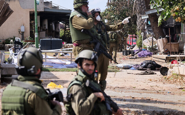 Israeli soldiers stand near the body of a Palestinian terrorist in Kfar Aza, in the south of Israel, bordering Gaza Strip on October 10, 2023. (Thomas COEX / AFP)