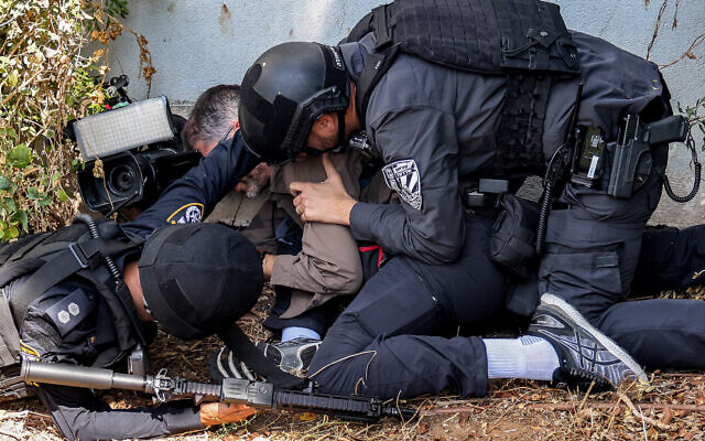 Security forces assist a journalist taking cover during an alert for a rocket attack in Sderot on October 12, 2023 (Menahem KAHANA / AFP)