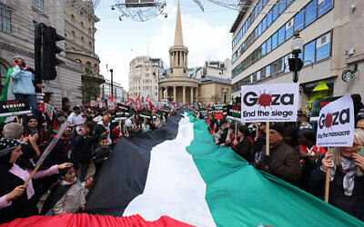 People gather with placards and a large Palestinian flag to take part in a 'March For Palestine' in London on October 14, 2023 (Photo by Adrian DENNIS / AFP)