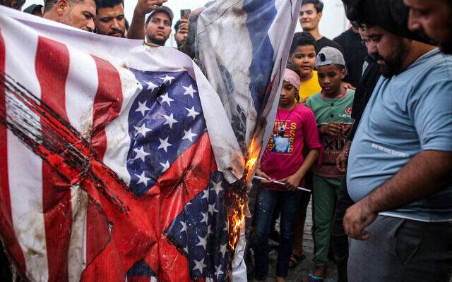 Demonstrators burn banners showing the US and Israeli flags during a demonstration in solidarity with the Palestinian people in the Gaza Strip, in Iraq's southern city of Basra on October 20, 2023. (Hussein Faleh/AFP)