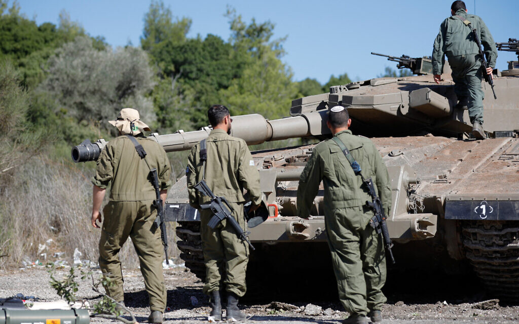Israeli soldiers stand near a Merkava tank as they man a position at an undisclosed location on the border with Lebanon on October 21, 2023 (Jalaa MAREY / AFP)