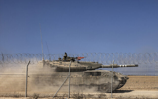 A Merkava tank drives past a fence near Kibbutz Be'eri, close to Israel's border with Gaza, on October 20, 2023, in the aftermath of an attack by Palestinian terrorists on October 7. (RONALDO SCHEMIDT / AFP)