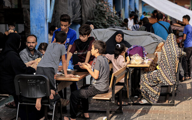 Members of a family sit together in the playground of a school run by the United Nations Relief and Works Agency for Palestine Refugees (UNRWA) agency that has been converted into a shelter for displaced Palestinians in Khan Yunis in the southern Gaza Strip on October 25, 2023. (MAHMUD HAMS / AFP)