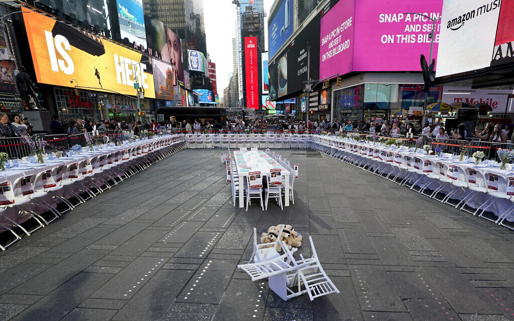The Israeli-American Council, American Jewish Committee, and other Jewish groups unveil an installation in Times Square October 26, 2023 featuring a 222-seat Shabbat table with a chair and place setting for hostages held by Hamas. (TIMOTHY A. CLARY / AFP)