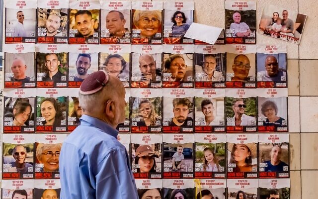 A man walks past posters of Israelis held hostage in Gaza during a protest in solidarity with the hostages' families, in Rehovot, October 29, 2023. (Meir Conforti / Protest Organizers)
