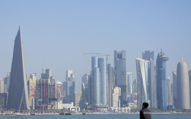 With the city skyline in the background, a man sits at Doha corniche in Doha, Qatar, November 22, 2022. (AP Photo/Lee Jin-man)