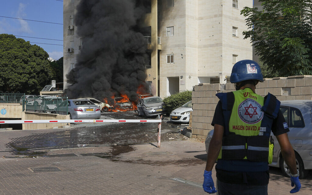 Cars are burning after a rocket fired from the Gaza Strip hit a parking lot and a residential building in Ashkelon, October 7, 2023 (AP Photo/Tsafrir Abayov)