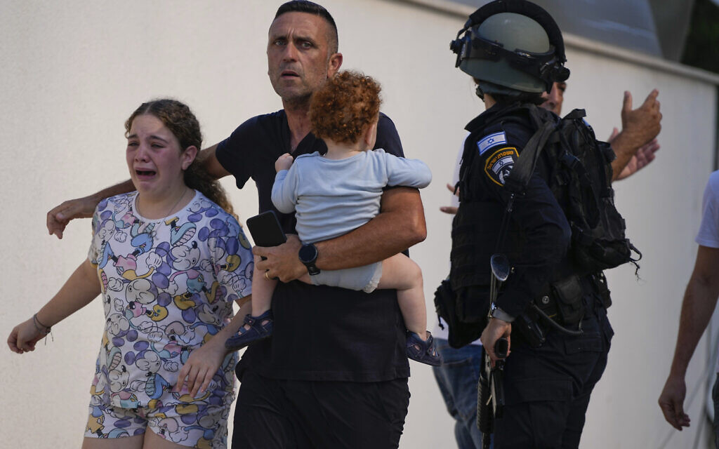 Israeli police officers evacuate a family from a site hit by a rocket fired from the Gaza Strip, in Ashkelon, October 7, 2023. (AP Photo/Tsafrir Abayov)
