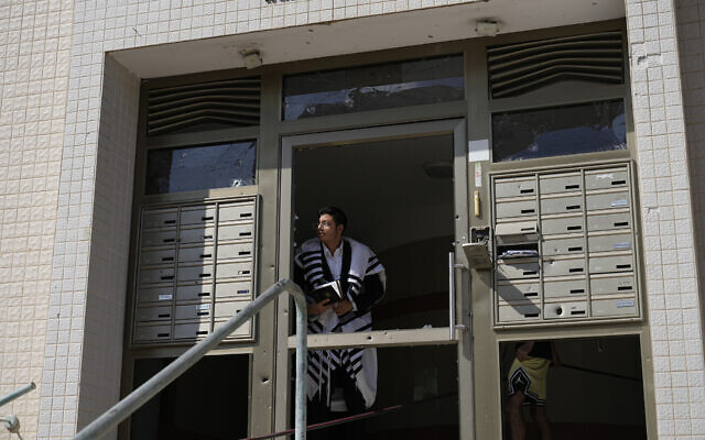 An ultra-Orthodox Jew peers out of a building after a rocket attack from the Gaza Strip in Ashkelon, October 7, 2023. (AP Photo/Ohad Zwigenberg)