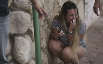 Israelis take cover from incoming rocket fire from the Gaza Strip in Ashkelon, southern Israel, October 11, 2023. (AP Photo/Leo Correa)