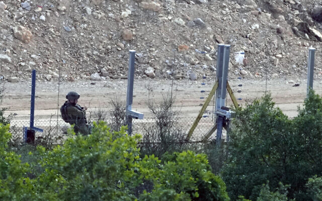 An Israeli soldier adds a new fence alongside the border wall with Lebanon as seen from the Lebanese side of the Lebanese-Israeli border in the southern village of Marwaheen, Lebanon, Friday, Oct. 13, 2023.(AP Photo/Hassan Ammar)
