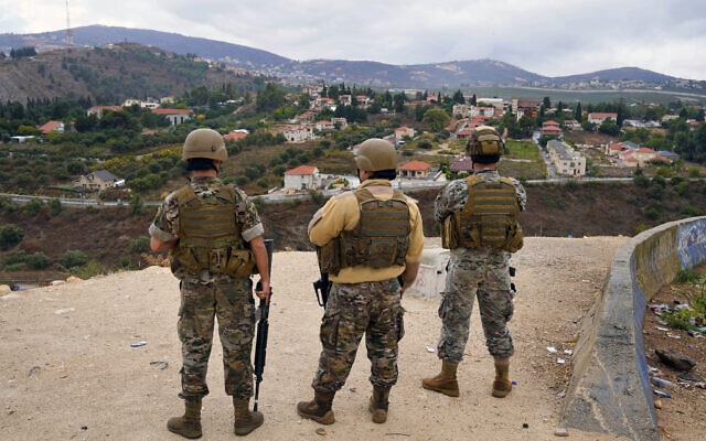 Lebanese army soldiers stand guard as they face the Israeli town of Metula, background, in the southern border village of Kfar Kila, Lebanon, Sunday, Oct. 15, 2023.  (AP Photo/Bilal Hussein)