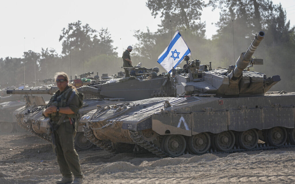 Israeli soldiers work on a tank at a staging area near the border with the Gaza Strip, in southern Israel, October 20, 2023. (AP Photo/ Ohad Zwigenberg)