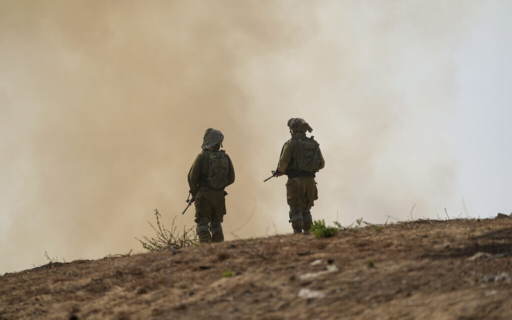 Israeli soldiers stand next to a burning field near the border with the Gaza Strip, in southern Israel, October 24, 2023. (AP/Ohad Zwigenberg)
