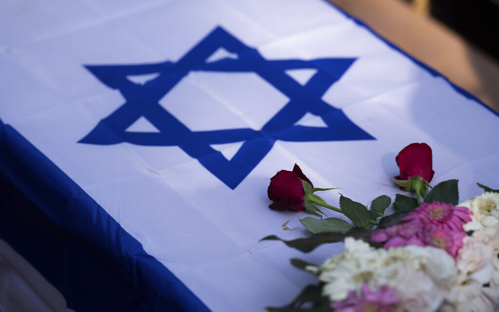 Flowers stand on a coffin draped with the Israeli flag during the funeral of Dana Bachar and her son Carmel, victims of the October 7 Hamas massacre in Kibbutz Be'eri, at the cemetery in Kibbutz Gan Shlomo, near Rehovot, October 24, 2023. (AP Photo/Petros Giannakouris)