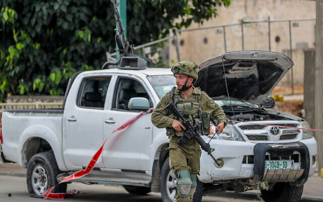 An Israeli soldier stands next to a vehicle used by Hamas terrorists in the southern Israeli city of Sderot, October 7, 2023. (Jamal Awad/Flash90)