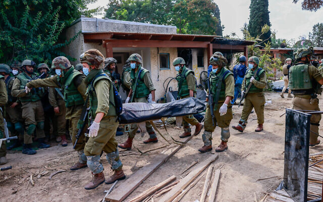 Israeli soldiers remove bodies of Israeli civilians in Kibbutz Kfar Aza, near the Israeli-Gaza border in southern Israel, October 10, 2023. (Chaim Goldberg/Flash90)