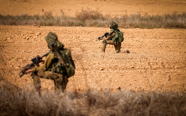 Israeli soldiers takes position on a main road near the Israel-Gaza border in southern Israel, October 10, 2023. (Chaim Goldberg/Flash90)