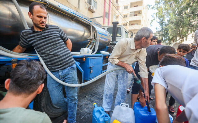 Palestinians fill water containers in the street in Gaza City, October 12, 2023. (Atia Mohammed/Flash90)