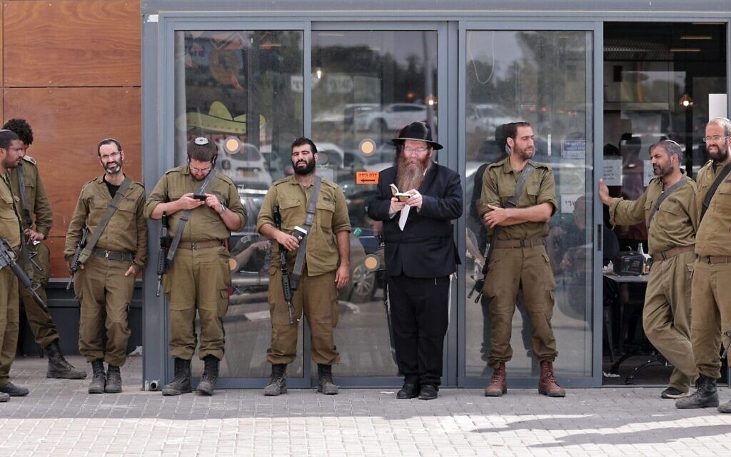 Israeli soldiers pray with a rabbi during a break in the southern Israeli city of Beit Kama, October 16, 2023. (Thomas Coex/AFP)