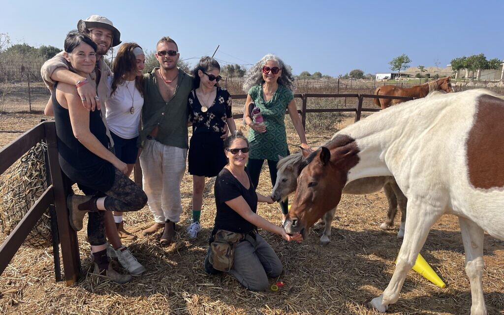 Survivors from the Supernova trance festival bond with horses at the Dror family's horse farm at Moshav Ofer, northern Israel, October 31, 2023. (Sue Surkes/Times of Israel)