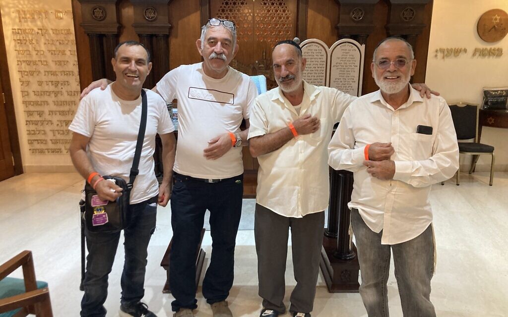 Four Sderot men show bracelets identifying them as evacuees, after evening prayers, Royal Dead Sea Hotel, October 30, 2023. (Mati Wagner/Times of Israel)
