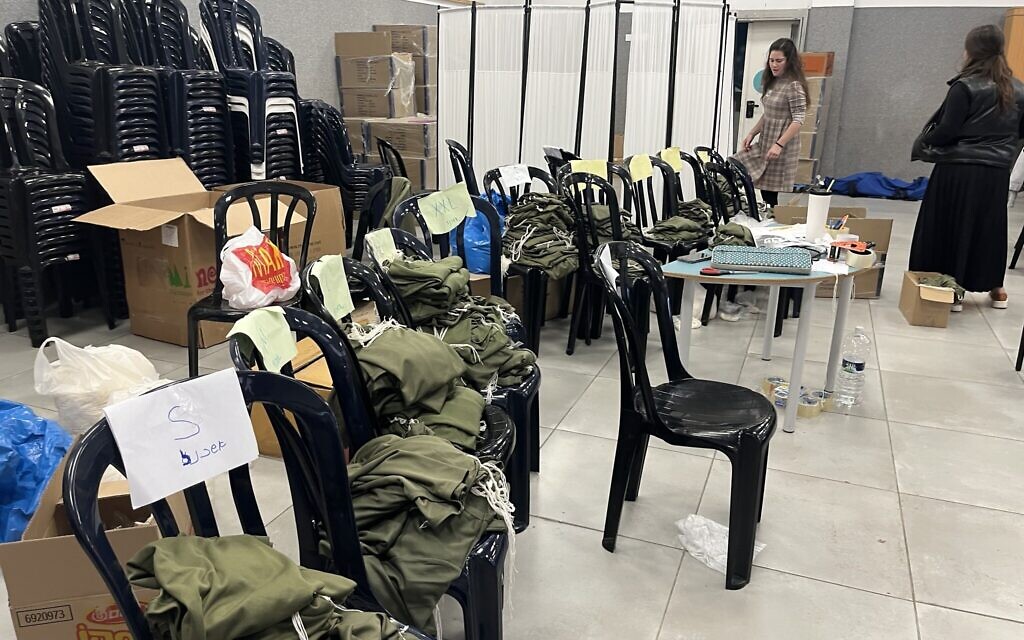 Piles of army vests and tzitzit strings are seen set up in a school hall in Jerusalem as community members prepare tzitzit for IDF soldiers on the front lines, October 19, 2023. (Shira Silkoff)