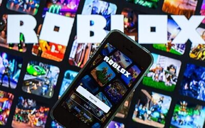 In this photo illustration, the Roblox app seen displayed on a smartphone screen and a Roblox logo in the background. (Thiago Prudêncio/SOPA Images/LightRocket via Getty Images via JTA)