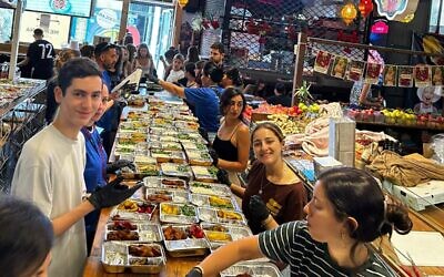 Israeli volunteers, including dozens of teenagers, at work at Shuk Tzafon market in Tel Aviv making meals for Israeli soldiers and others in need, October 12, 2023. (Bar Mandel/JTA)