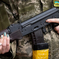 FILE - A Ukrainian civil defense member holds a Kalashnikov assault rifle while patrolling in Kyiv, Ukraine, February 27, 2022. (AP Photo/Efrem Lukatsky, File)