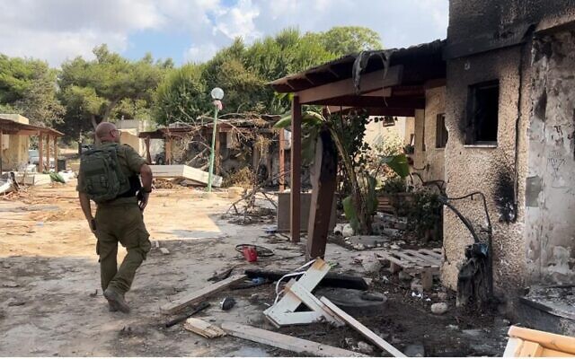 A soldier walks through Kfar Aza, October 16, 2023. (Lazar Berman/The Times of Israel)