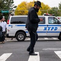 A man walks as police patrol a neighborhood in Brooklyn with a large Orthodox Jewish community on October 12, 2023, in New York City. (Spencer Platt/ Getty Images/AFP)