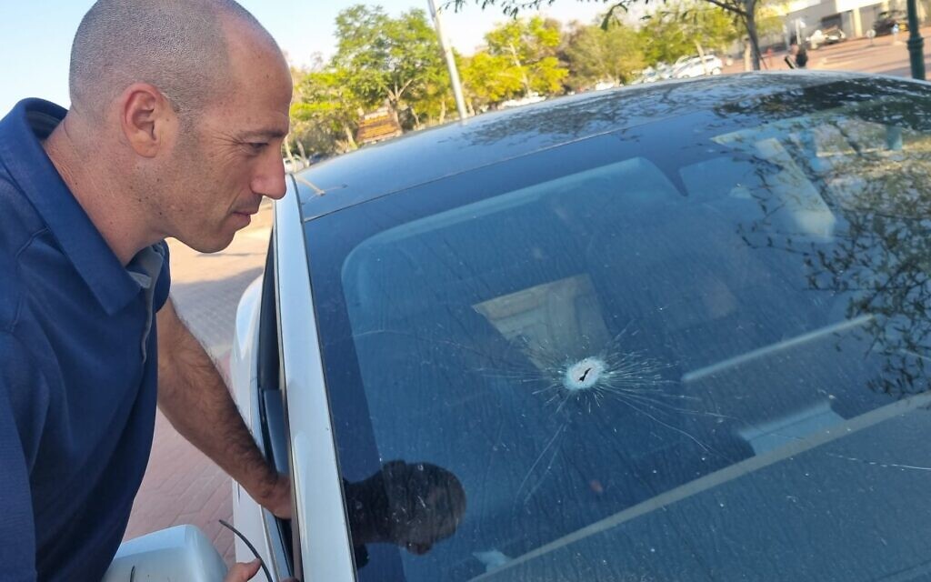 Yftach Gepner of Moshav Ein Habesor inspects the bullet hole in his car. (Courtesy Ynet)